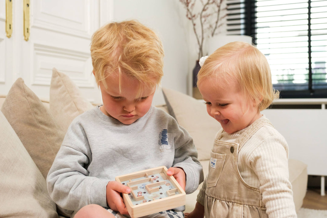 Two children play together with the Mini Wooden Labyrinth, a travel toy from Egmont