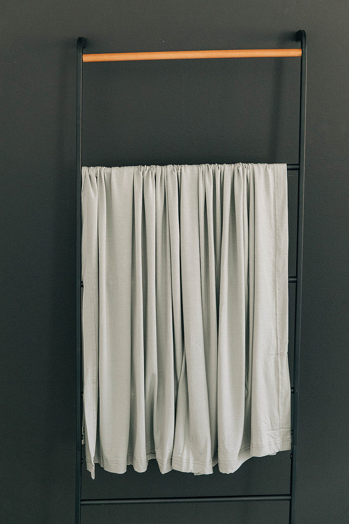 Sage Bamboo Stretch Swaddle by Mebie Baby, styled with matching nursery decor.