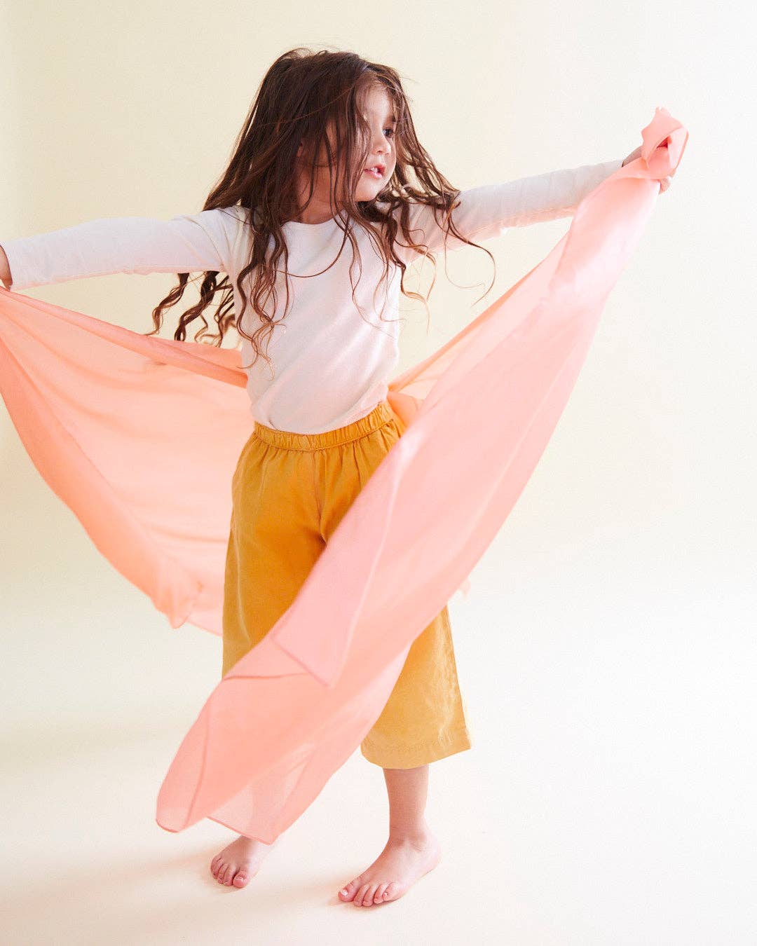 Child dancing with a peach Sarah's Silks Solid Color Playsilk, a top choice for creative play