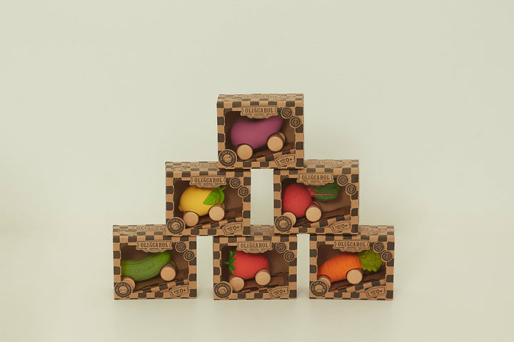 A stack of Oli & Carol fruit shaped push cars including the Sweetie the Strawberry design