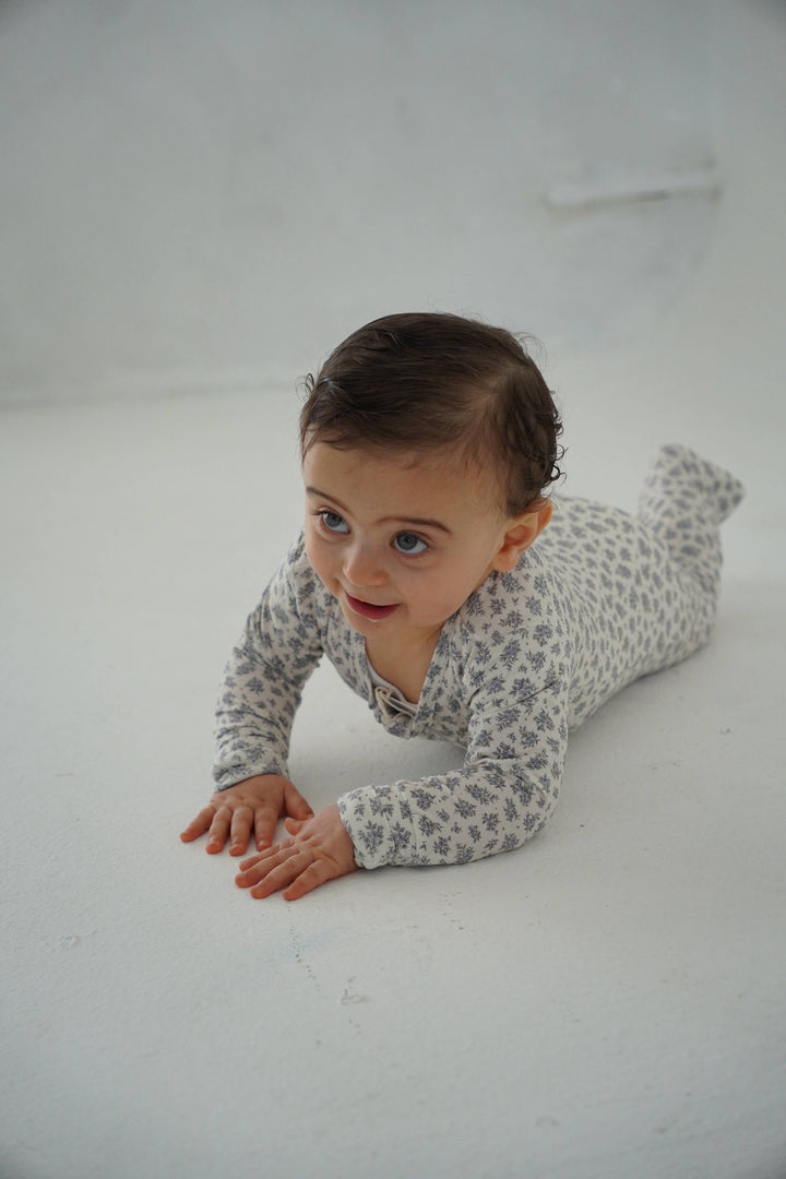 Baby crawling in Little Threads blue floral bamboo footie, flexible infant sleepwear for movement, play, naps, and comfortable sleep