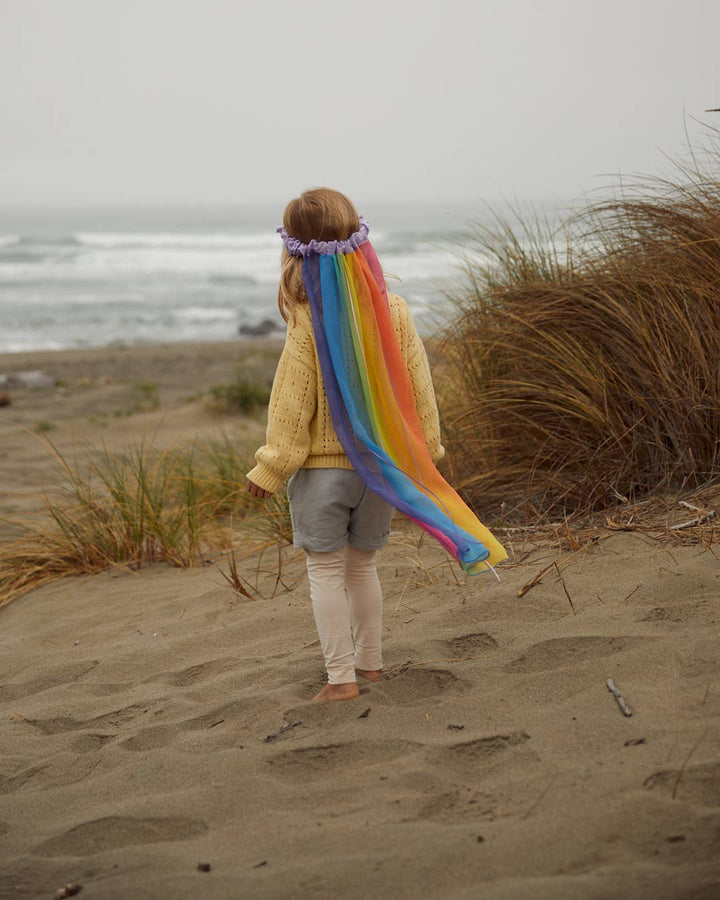 Child walking along the beach in a Sarah's Silks Rainbow Veil, a top pick for pretend play