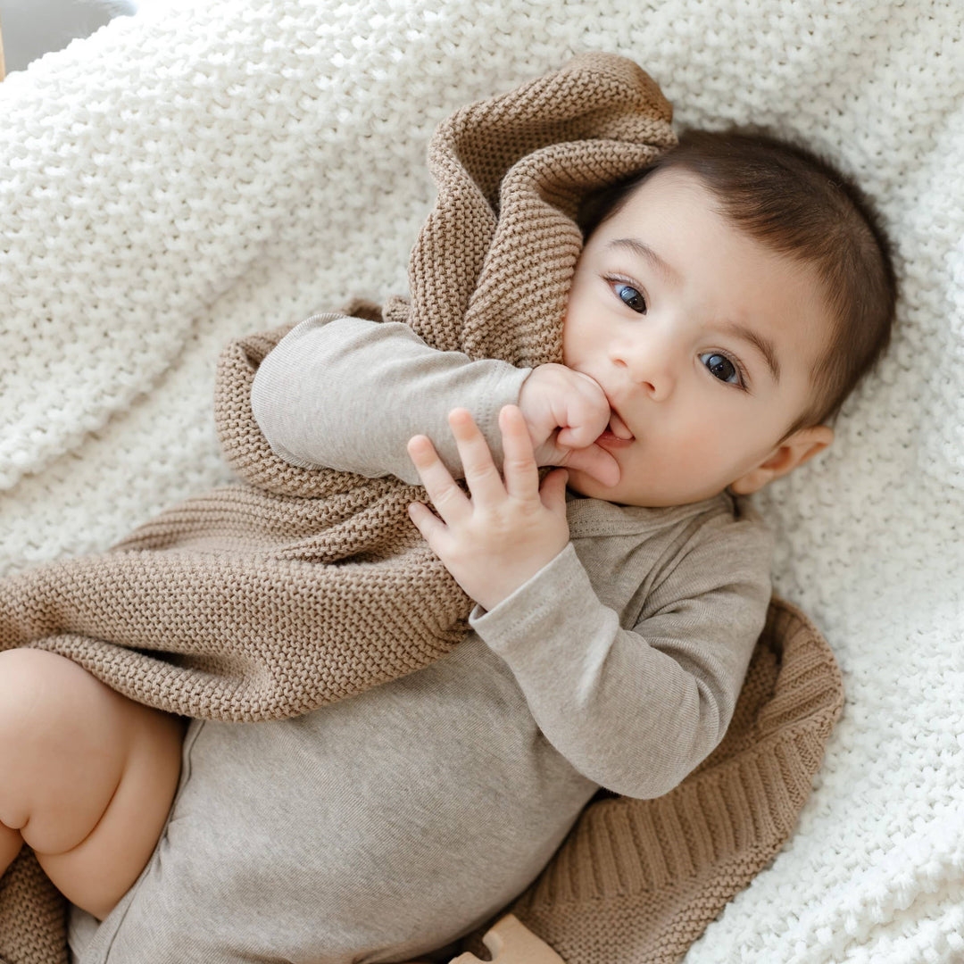 Baby holding the Bleu La La Heritage Knitted 100% Organic Cotton Swaddle in Hunter Green