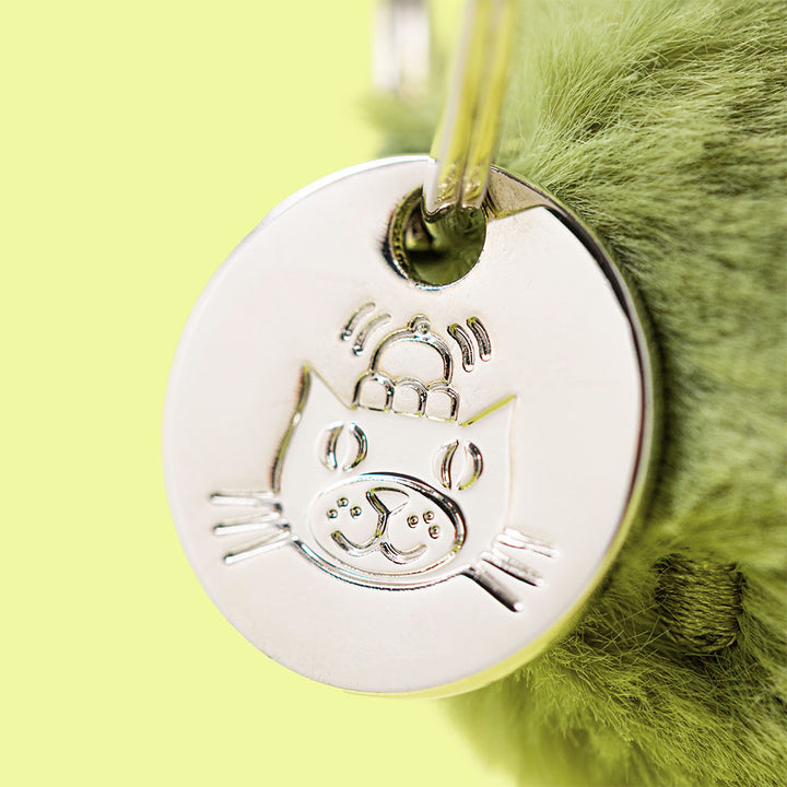 Jellycat Amuseables Pickle Bag Charm close up silver charm tag detail with smiling pickle character plush bag accessory premium Jellycat collectible