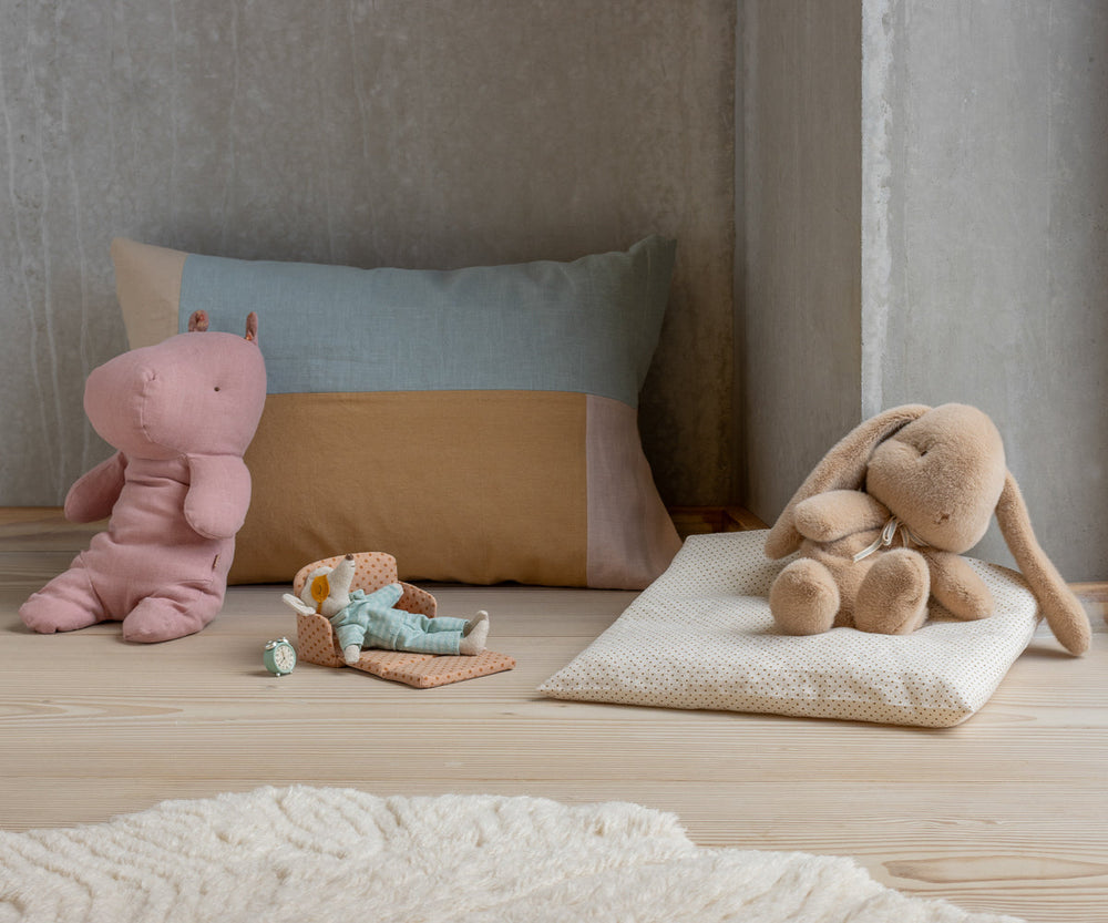 Maileg Medium Rose Hippo stuffed animal displayed in calm nursery setting with pillows and soft toys