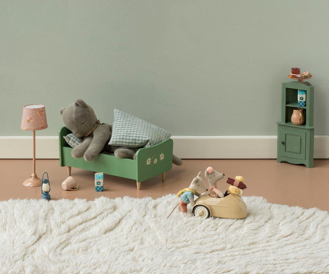 Little Sister mouse resting on a green bed in a cozy dollhouse nursery scene by Maileg