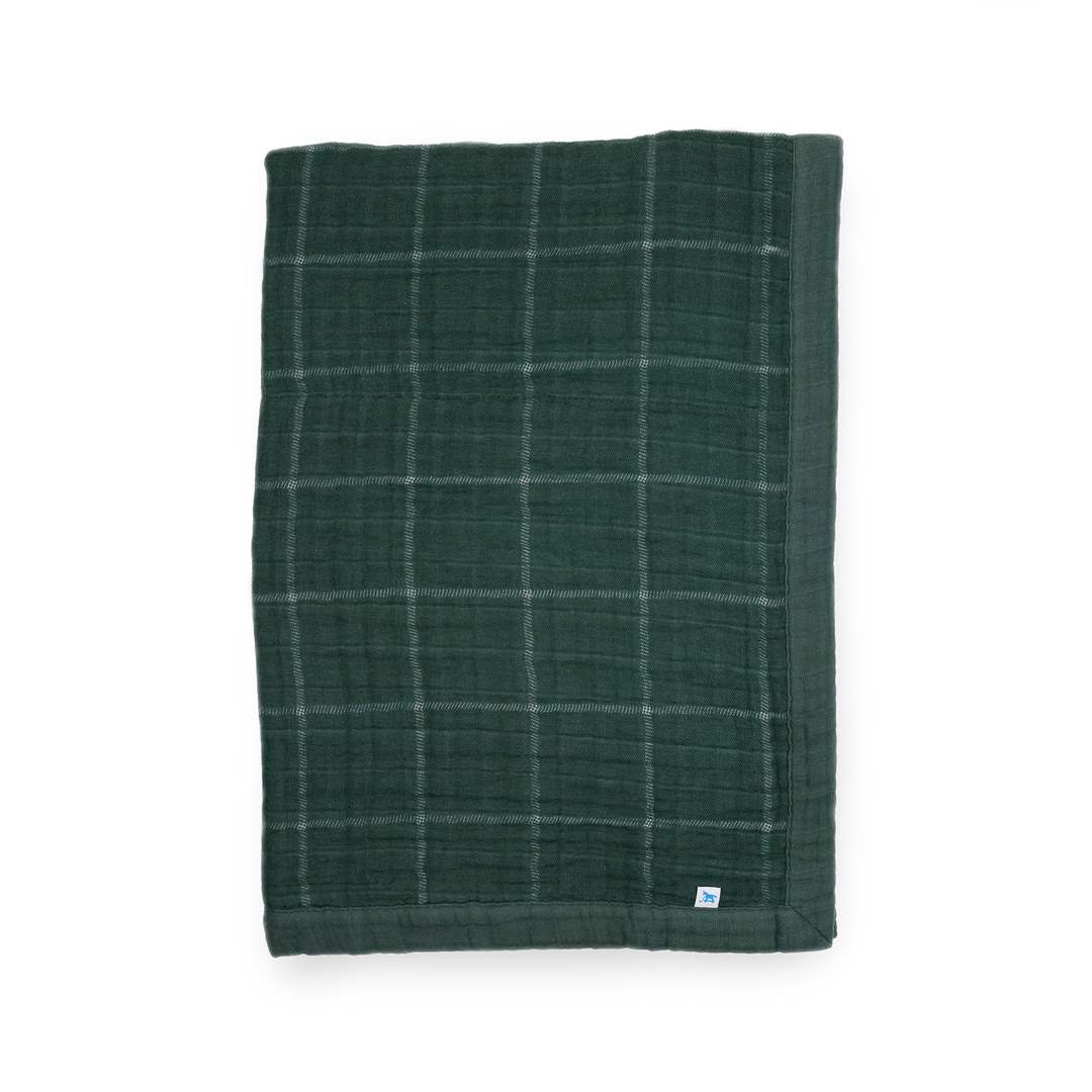 Little Unicorn Cotton Muslin Baby Quilt - Evergreen Plaid displayed in a classic green plaid, a cozy baby blanket for nursery or stroller.