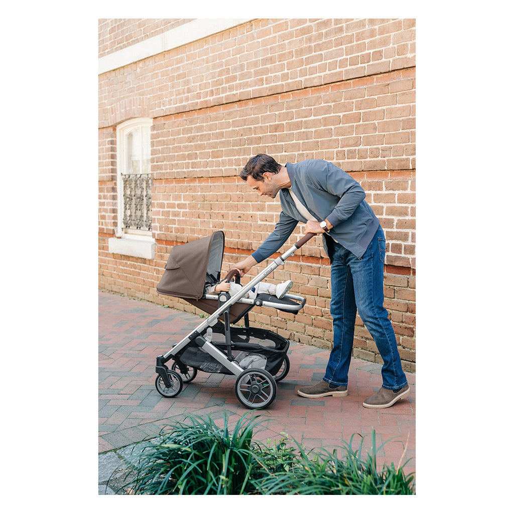 Man attending to infant while in cruz stroller by Uppababy