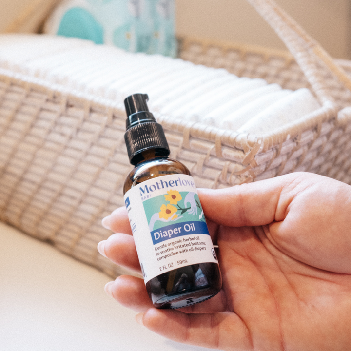 Flat lay of Motherlove Diaper Oil bottle, a clean and organic formula perfect for everyday baby oil care.