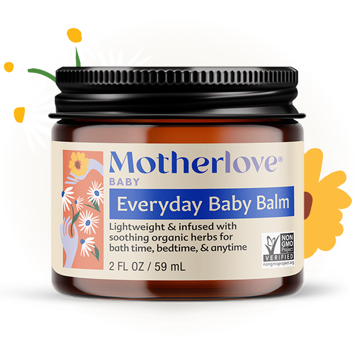 Motherlove Everyday Baby Balm pictured with fresh herbs, a soothing moisturizing skin balm for delicate baby skin.