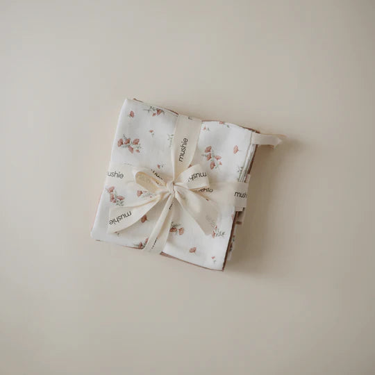 Mushie organic baby washcloths styled flat lay - five soft muslin cotton cloths in pastel tones on minimal background