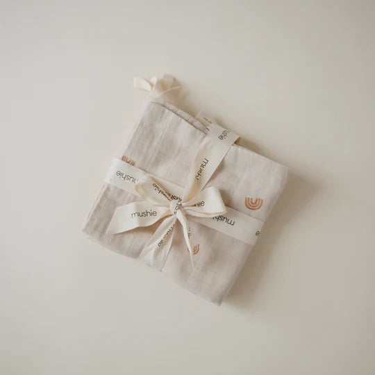 Mushie muslin baby washcloths December flat lay - soft organic cotton 5-pack with hanging loop displayed on neutral surface