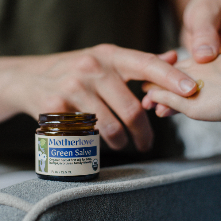 A close-up of Motherlove Green Salve jar showing smooth texture and rich, herbal moisturizing skin balm formula.