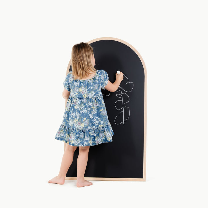Girl touches the black chalkboard side of this Gathre easel, ready for doodling