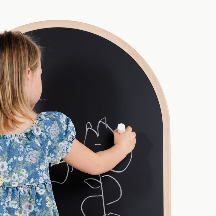 Child draws with chalk on the black side of Gathre's arched chalkboard and whiteboard