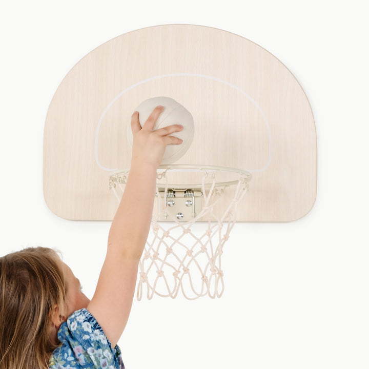 Close up of a child reaching to shoot on this wooden hoop from Gathre, mounted indoors
