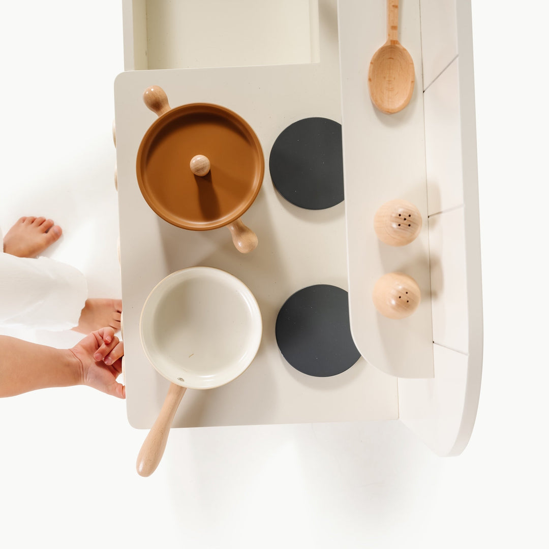 Overhead view of small hands arranging metal cookware on a play kitchen from Gathre