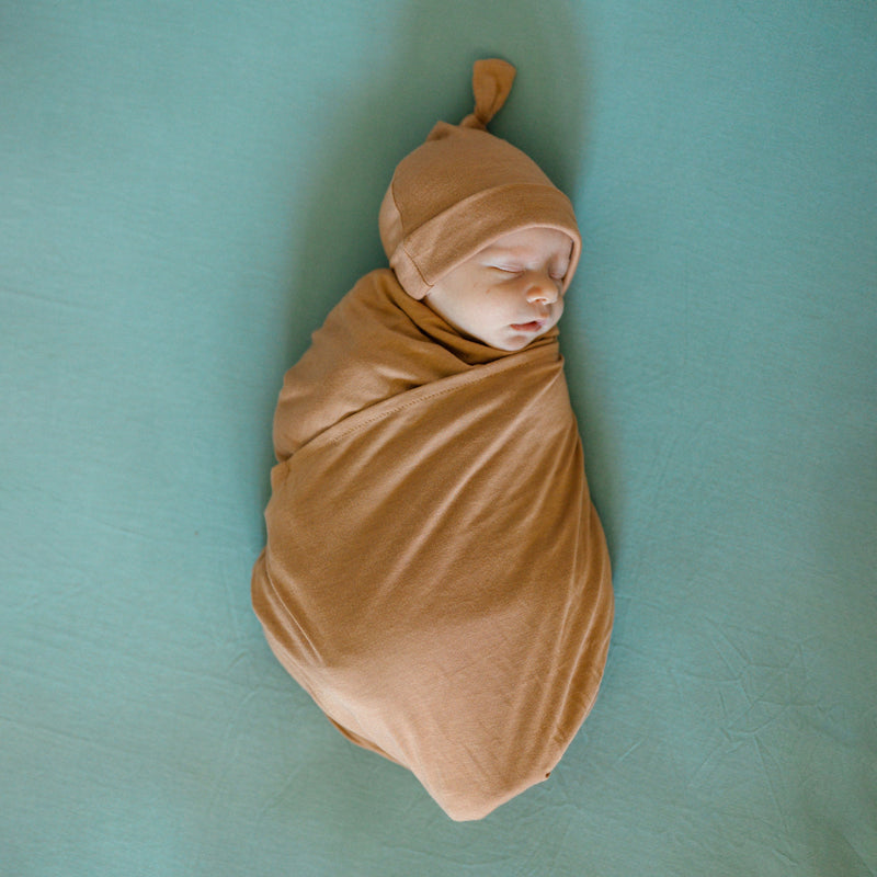 Styled with a terracotta blanket, the Little Unicorn Stretch Knit Crib Sheet - Harbor stands out among organic crib sheets.