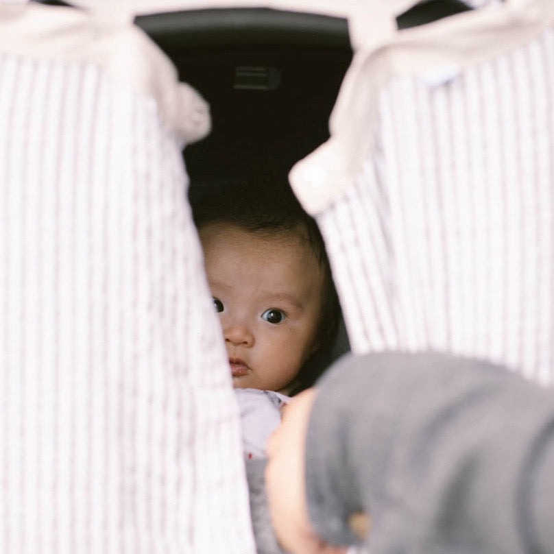 Little Unicorn Cotton Muslin Car Seat Canopy - Grey Stripe displayed on a car seat, offering cozy shade and everyday versatility.