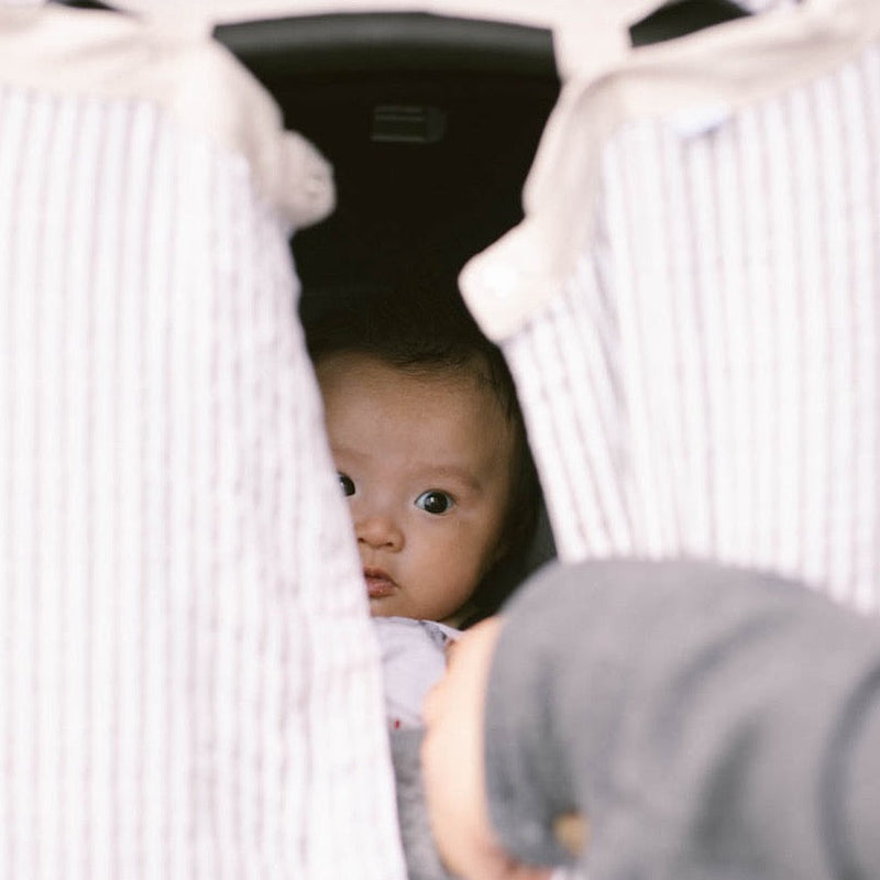 Little Unicorn Cotton Muslin Car Seat Canopy - Grey Stripe displayed on a car seat, offering cozy shade and everyday versatility.