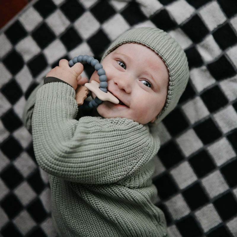 Infant chewing on Mushie space-colored teething ring