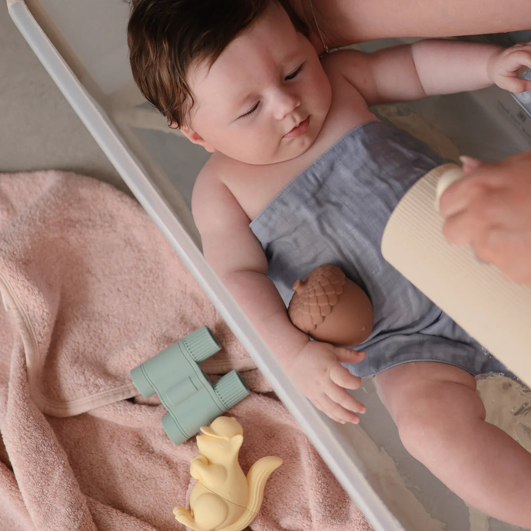 Child playing with Mushie Nature Mold Free Bath Set - toddler holding nature-themed silicone bath toys outdoors
