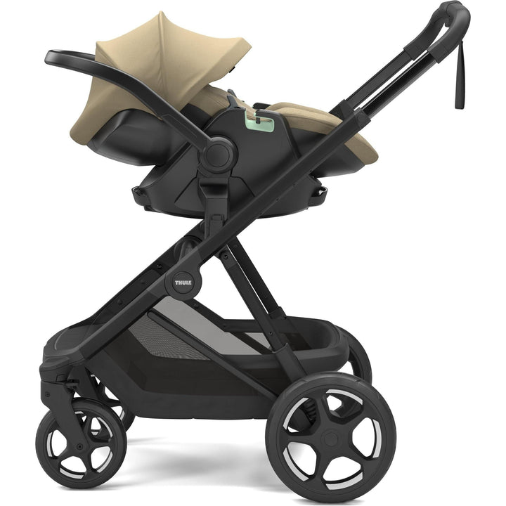 Faded khaki on black Thule Charm Stroller full-size stroller from birth, with Thule Maple car seat, side view