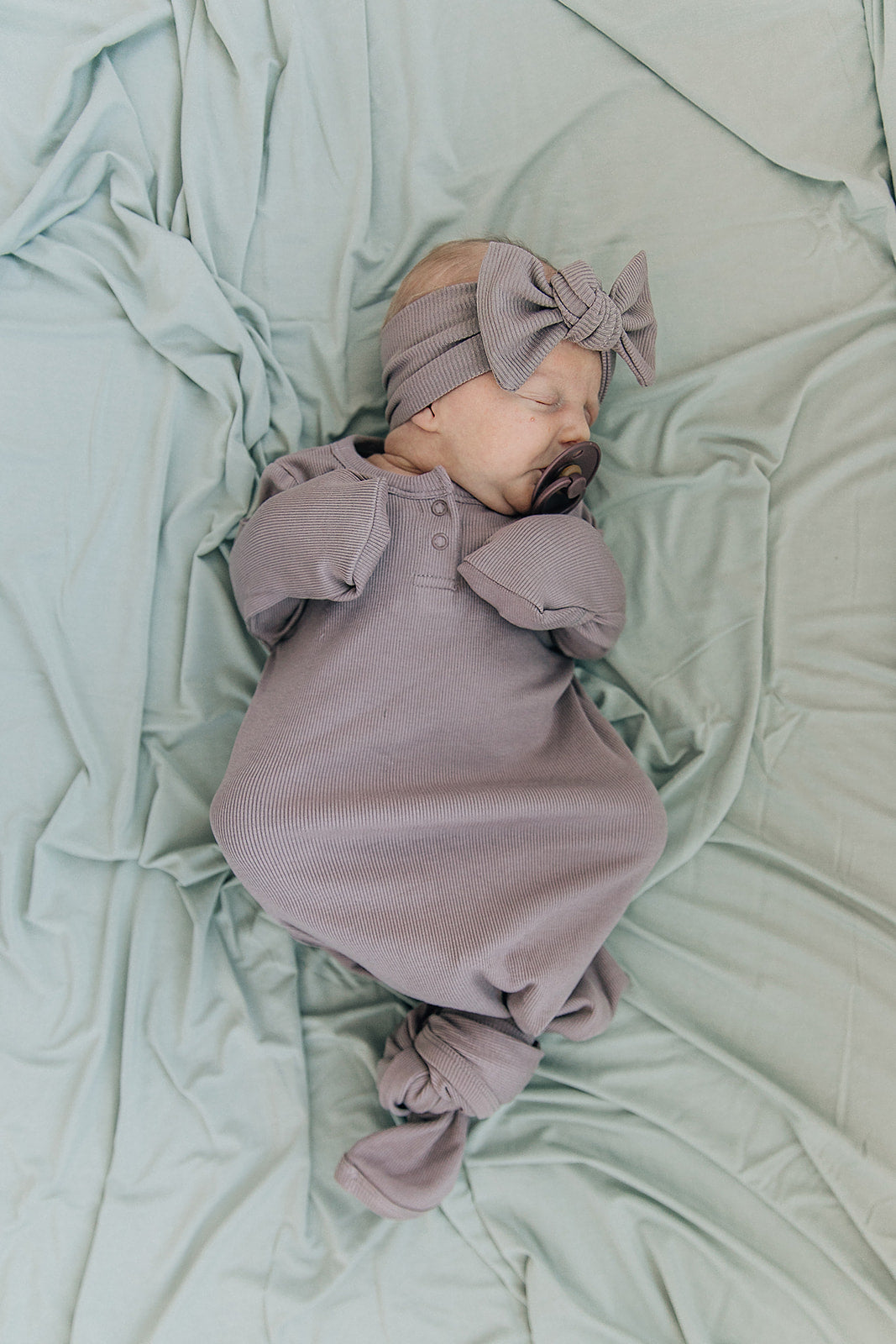 Sage Bamboo Stretch Swaddle from Mebie Baby, wrapped around a sleeping newborn.