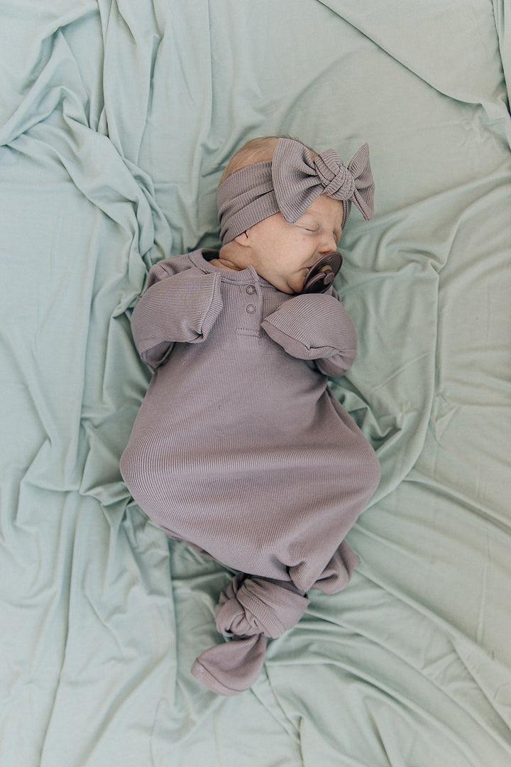 Sage Bamboo Stretch Swaddle from Mebie Baby, wrapped around a sleeping newborn.