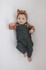 Baby wearing the organic dusty rose ribbed body suit and overalls