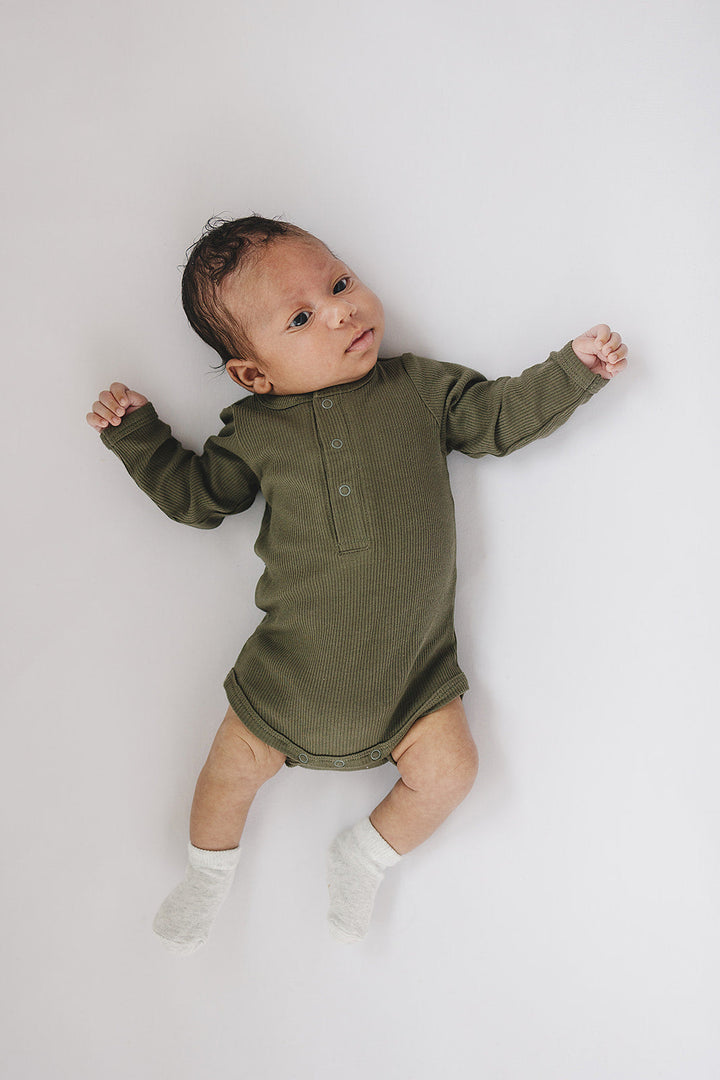 Mebie Baby Winter Green Organic Snap Long Sleeve Ribbed Bodysuit pictured alongside coordinating baby accessories