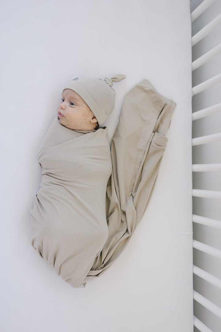 Shown in a flat lay to highlight the fabric, the Mebie Baby Oatmeal Bamboo Stretch Swaddle.