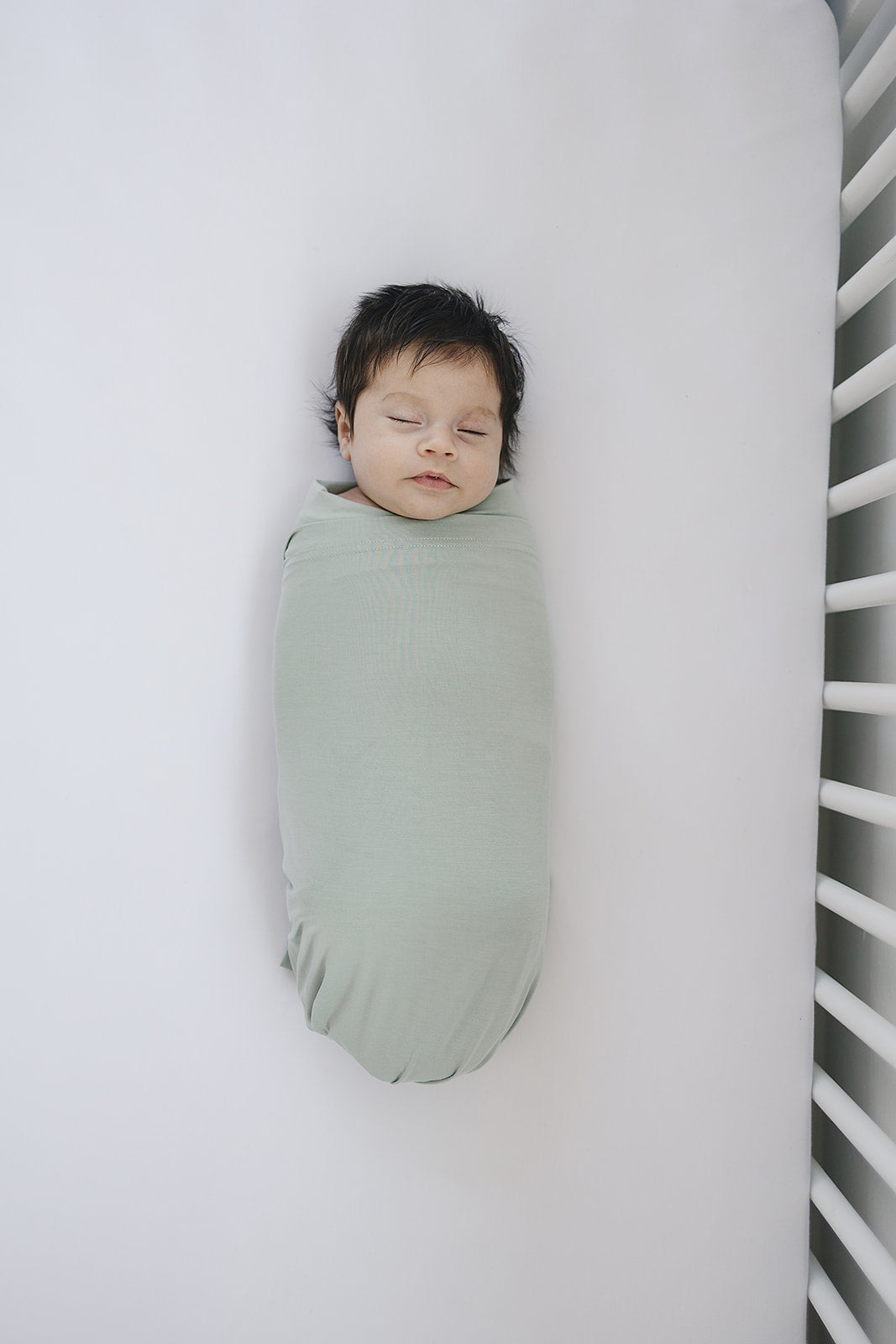 Mebie Baby Sage Bamboo Stretch Swaddle held up to show the soft stretch fabric.