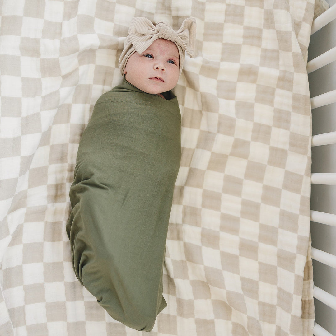 Breathable bamboo swaddle blanket for newborns, the Olive Bamboo Stretch Swaddle shown in a flat lay to highlight the fabric.