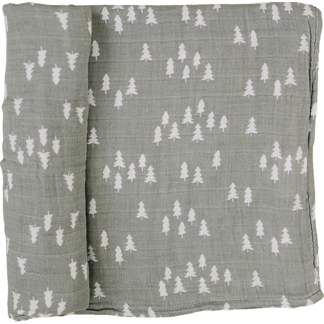 Pines Muslin Swaddle Blanket by Mebie Baby, folded on a nursery shelf.