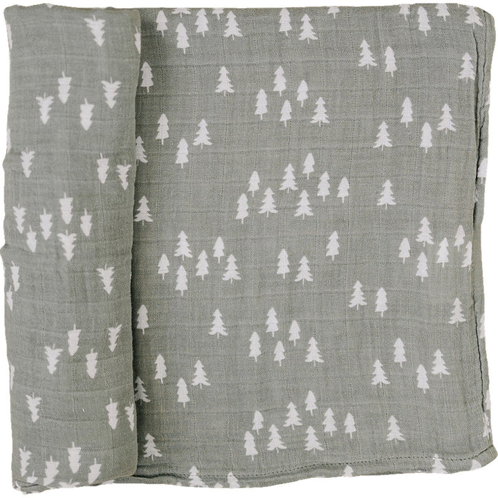 Pines Muslin Swaddle Blanket by Mebie Baby, folded on a nursery shelf.