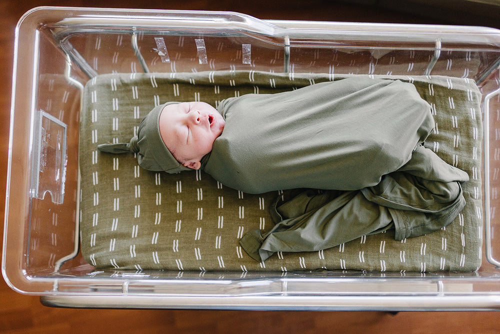 Wrapped around a sleeping newborn, the Olive Bamboo Stretch Swaddle from Mebie Baby.