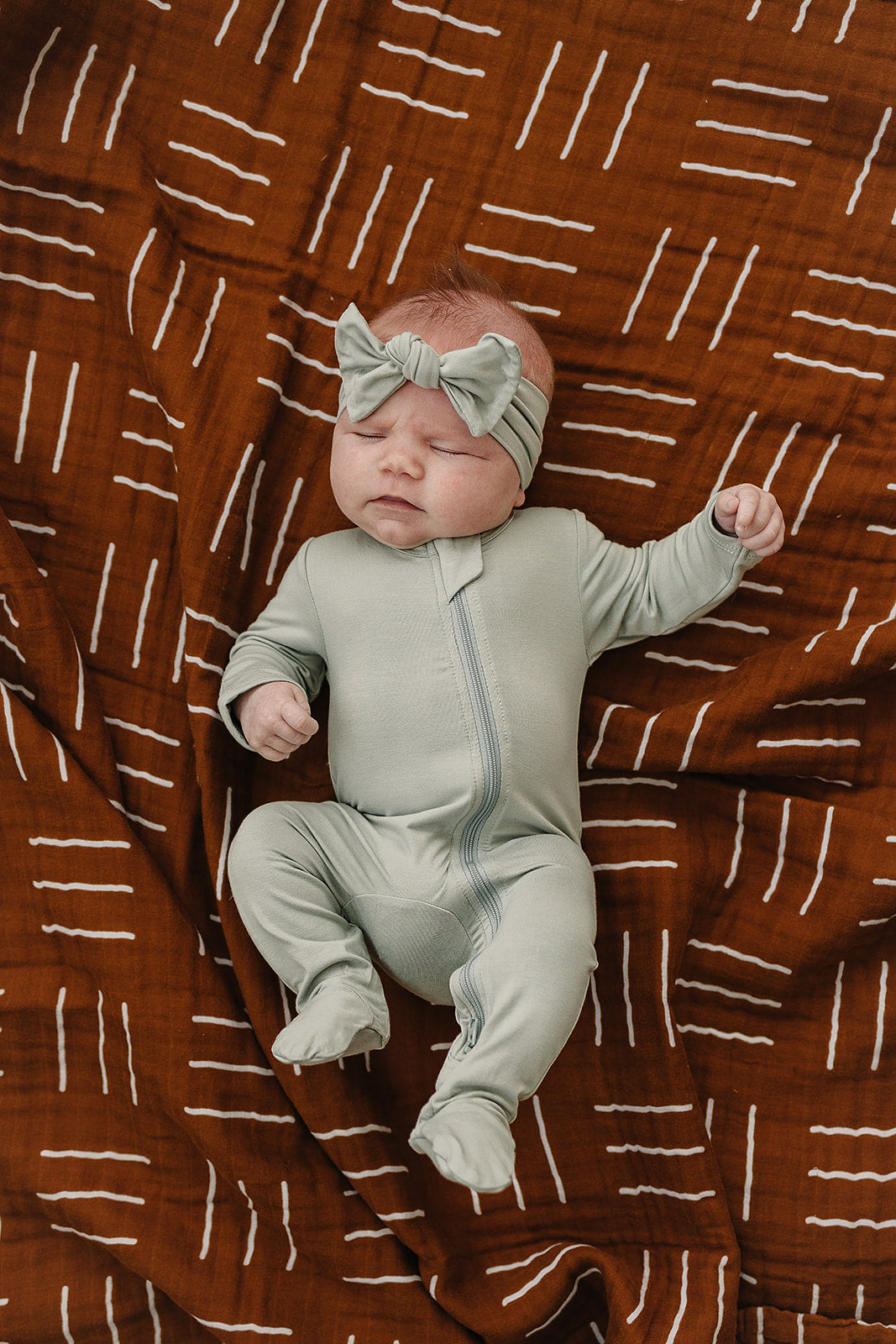 Mebie Baby Sage Bamboo Footed Zipper pictured alongside coordinating baby accessories