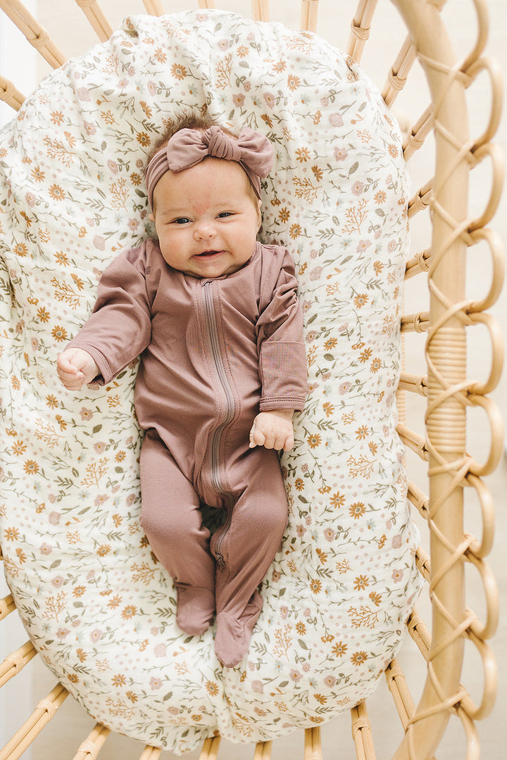 Baby modeling the Mebie Baby Plum Bamboo Footed Zipper, a soft zipper baby pajama for everyday wear
