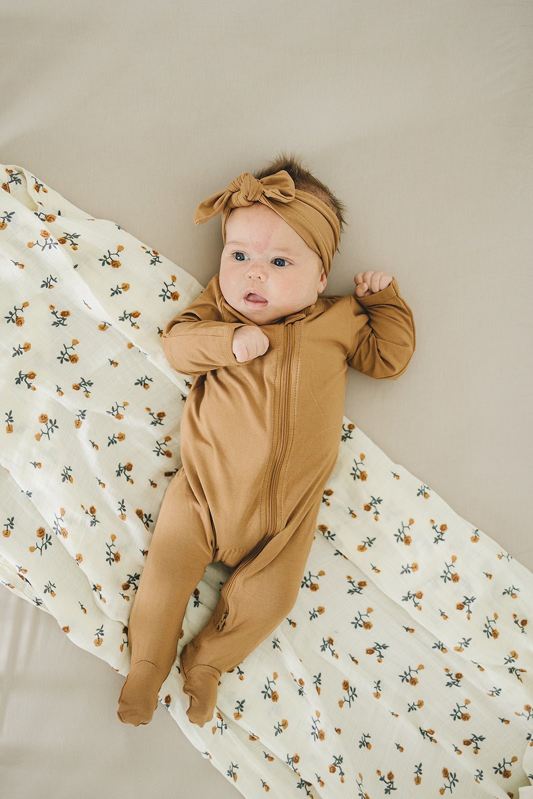 Baby modeling the Mebie Baby Mustard Bamboo Footed Zipper, a soft footed baby pajama for everyday wear