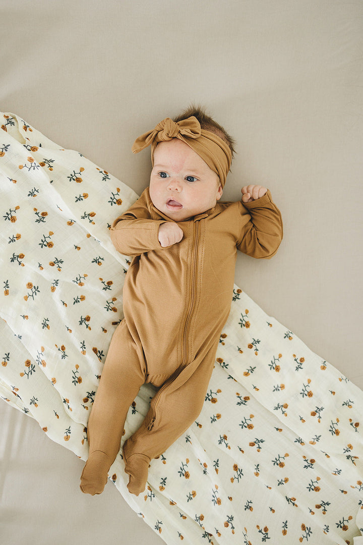 Baby modeling the Mebie Baby Mustard Bamboo Footed Zipper, a soft footed baby pajama for everyday wear