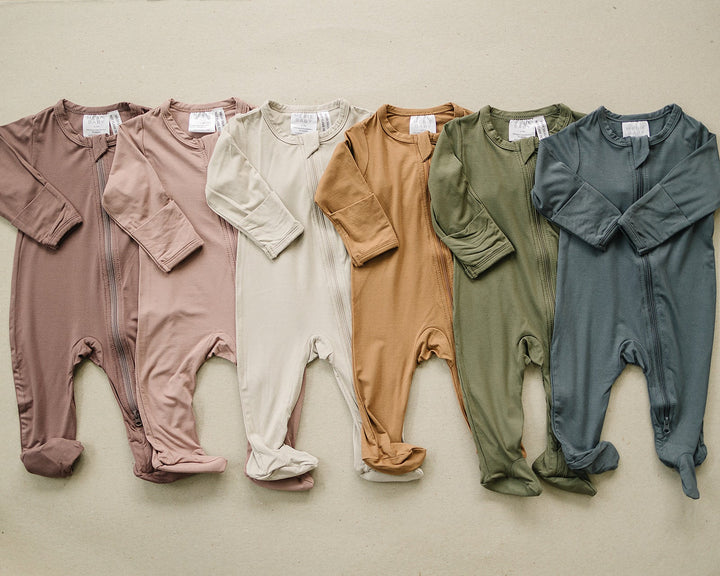 Styled flat lay of the Plum Bamboo Footed Zipper, a popular bamboo footie pajama from Mebie Baby