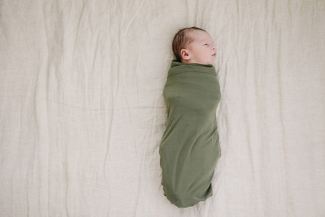 Mebie Baby Olive Bamboo Stretch Swaddle held up to show the soft stretch fabric.