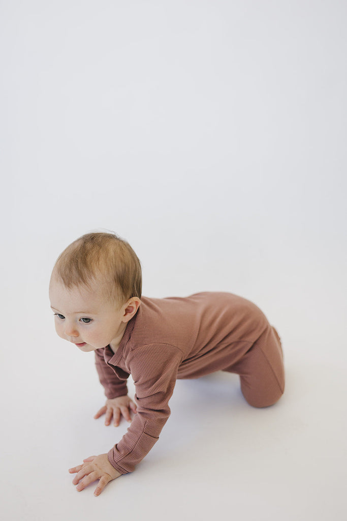 Baby crawling while wearing the footed cotton Mebie Baby one-piece