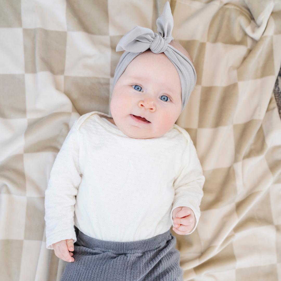 The Saranoni Minky Stretch Receiving Blanket in Neutral Checkered adds a modern touch and makes a sweet baby girl blanket gift.