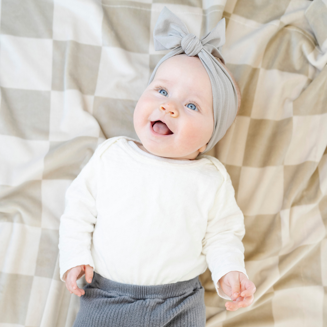 Bring texture and charm to the nursery with the Saranoni Minky Stretch Receiving Blanket in Neutral Checkered, a perfect baby boy blanket.