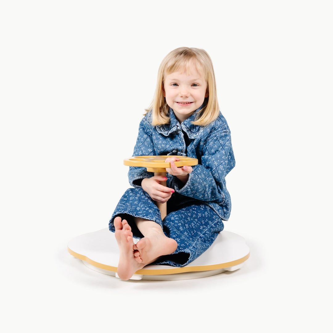 Toddler holds tight to the handle while spinning on this Gathre balance toy