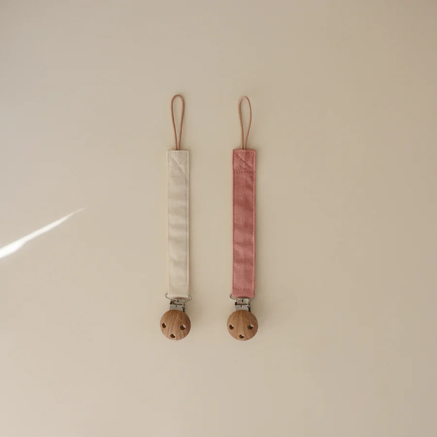 Timeless Dusty Rose and Shifting Sand Mushie Linen Pacifier Clip makes pacifiers easy to keep close and clean.