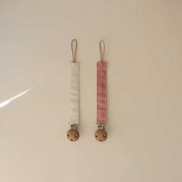 Timeless Dusty Rose and Shifting Sand Mushie Linen Pacifier Clip makes pacifiers easy to keep close and clean.