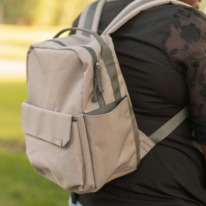 Lifestyle shot of the Little Unicorn Red Rovr Mini Roo Backpack - Truffle, ideal for travel and kids travel backpack adventures.